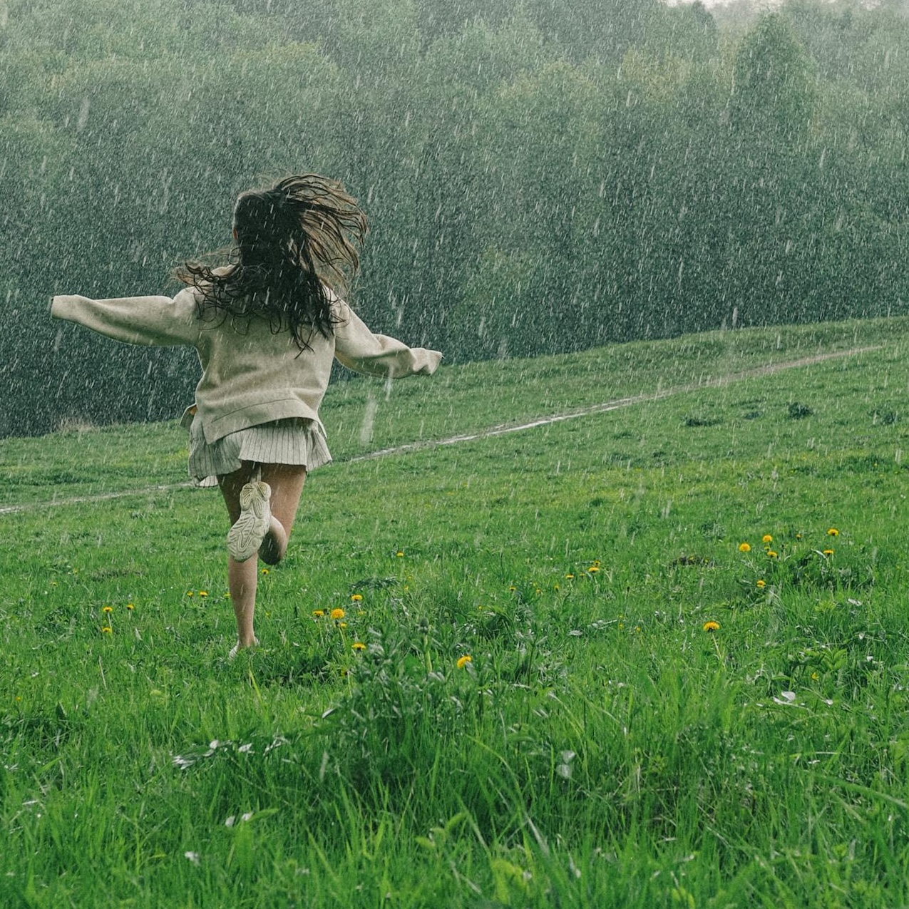 Person løber frit gennem græs i regn - symboliserer naturlig frihed og afslappethed